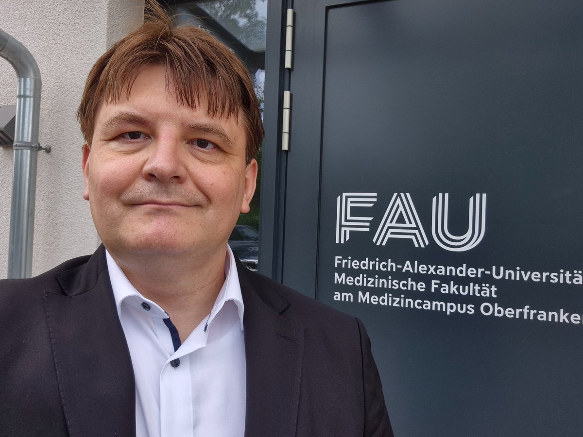 Adrian Lenhardt vor dem Eingang der FAU Medizinischen Fakultät am Medizin-Campus Oberfranken in Bayreuth